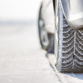 Close-up of car wheels rubber tire in deep snow. Transportation and safety concept.